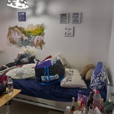 חדר מבולגן עם מיטה, שקיות ומוצרי טיפוח על שולחן