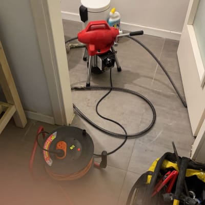 כלי עבודה של אינסטלטור, כולל מכונה אדומה וצינור