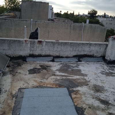 גג עם יריעות איטום אפורות ושכבת זפת שחורה