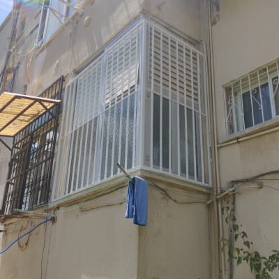 מסגרת מתכת סביב מרפסת סגורה עם תריסים