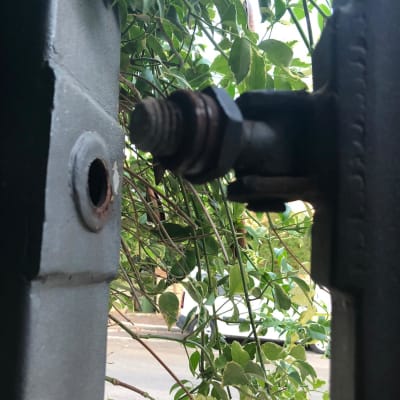 ציר מתכת של שער חשמלי עם עלים ברקע