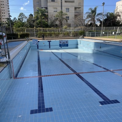 בריכה ריקה עם אריחים כחולים בתהליך שיפוץ