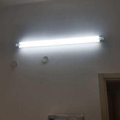 מנורת פלורסנט מוארת על קיר לבן