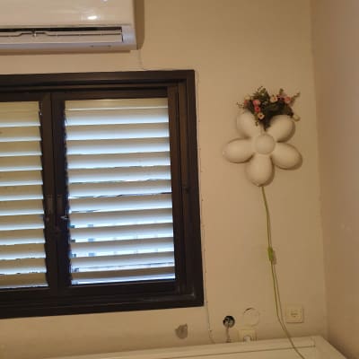 מזגן מותקן על קיר מעל חלון עם תריסים