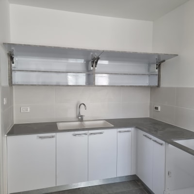 מטבח עם ארונות לבנים ומשטח עבודה אפור