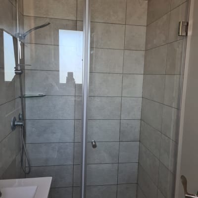 מקלחת עם דלת זכוכית, ראש מקלחת וקיר אריחים