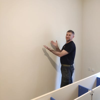 אדם מצביע על קיר צבוע בצבע בהיר