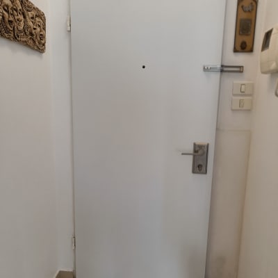 דלת לבנה עם ידית מתכת ובריח עליון