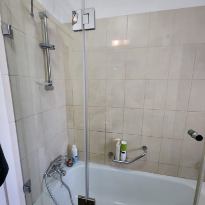 מקלחת עם אמבטיה, ברזים ומוצרי טיפוח על המדף