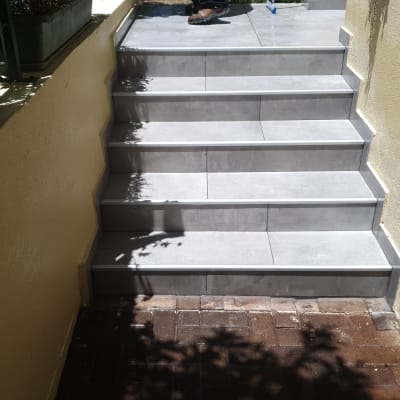 אדם מנקה מדרגות מרוצפות עם צינור מים