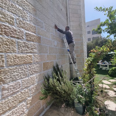 אדם על סולם אוטם קיר חיצוני באיטום