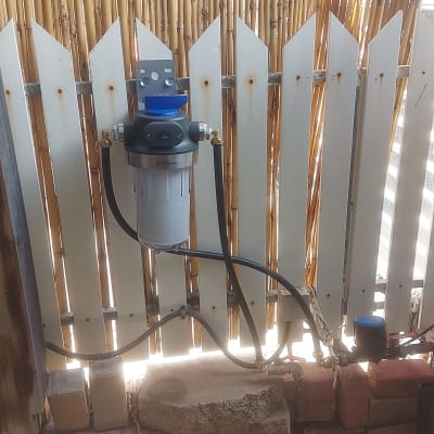 מסנן מים מותקן על גדר עם צינורות מחוברים