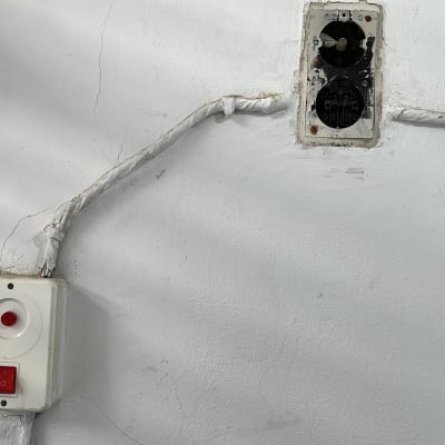 שקע חשמל פתוח עם חוטים חשופים על קיר לבן