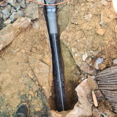 צינור ביוב מונח בתעלה באדמה עם כלי עבודה