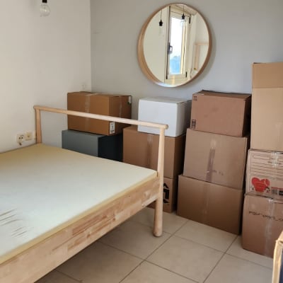 חדר עם מיטה מעץ וארגזים מסודרים בפינה