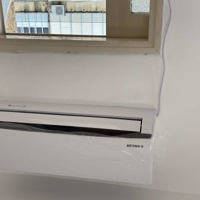 מזגן מותקן על קיר לבן עם חלון מעליו