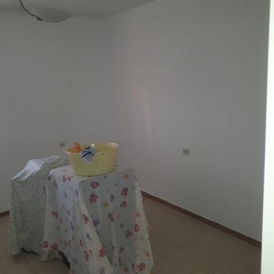 חדר עם קירות צבועים, דלי ומברשות על שולחן מכוסה