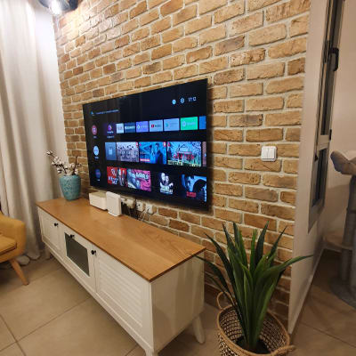 טלוויזיה תלויה על קיר לבנים עם תאורה