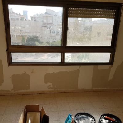 קיר עם תיקוני צבע וכלי עבודה לצביעה