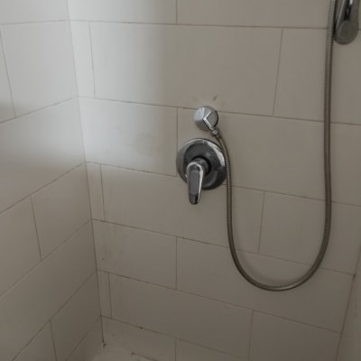 ברז מקלחת עם צינור מתכת על קיר אריחים