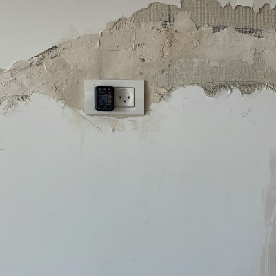 שקע חשמל עם בודק מתח על קיר טיח