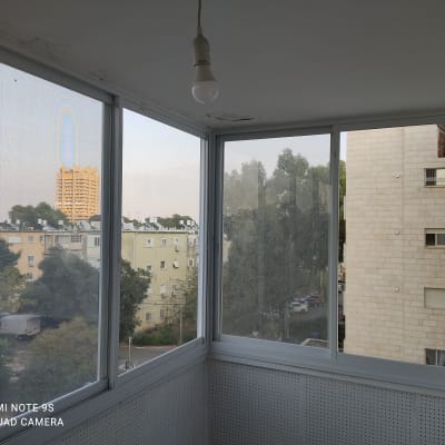 חלונות אלומיניום במרפסת סגורה עם נוף עירוני