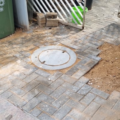 מכסה ביוב עגול על מדרכה מרוצפת