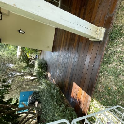 דק עץ חום ליד גינה ירוקה עם שיחים