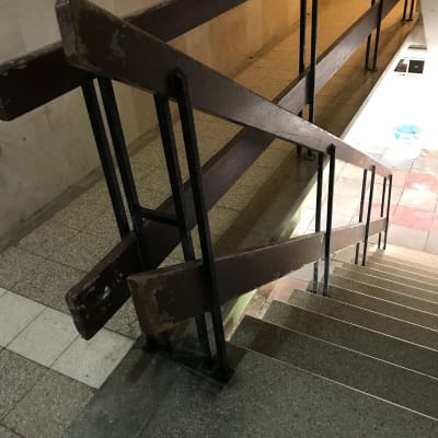 מעקה עץ חום עם מסגרת מתכת במדרגות