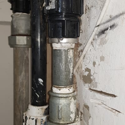 צינורות מתכת עם מחברים שחורים על קיר לבן