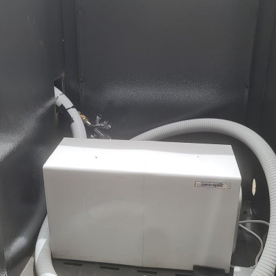 צינור לבן מחובר למכשיר סניטרי בארון מתכת