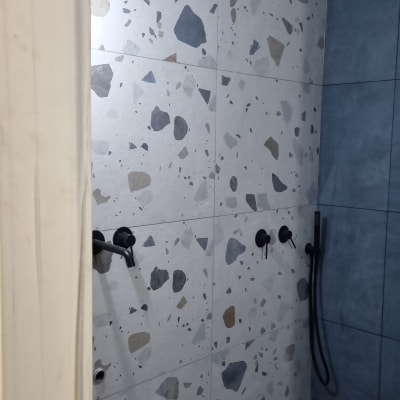 קיר מקלחת עם אריחי טרצו וברזים שחורים