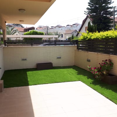 גינה עם דשא סינתטי, צינור השקיה ועציץ פרחים