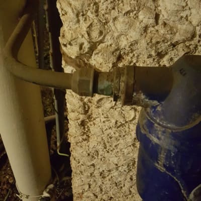 צינור מים עם ברז פלסטיק על קיר אבן