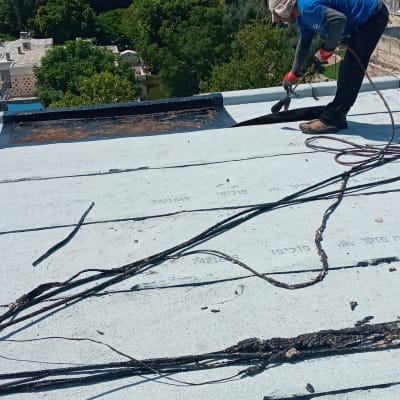 אדם מבצע איטום גג עם יריעות ביטומניות