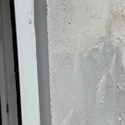 קיר מטויח עם מסגרת חלון לבנה