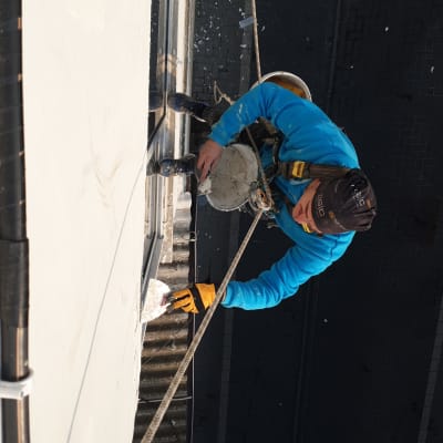 אדם על חבל מורח חומר איטום על קיר