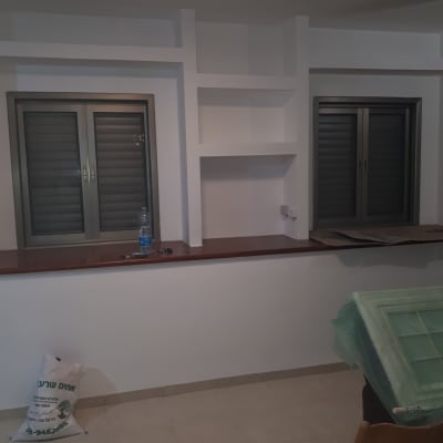 חלון עם תריסים, בקבוק מים, שקית על הרצפה