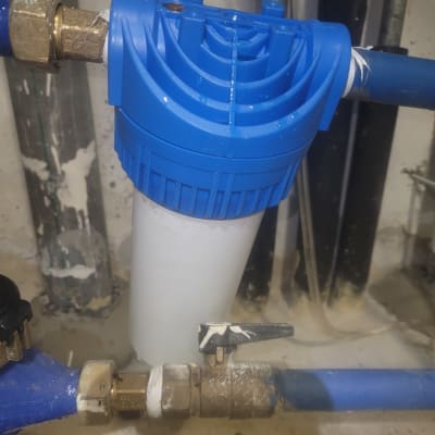 מסנן מים כחול מחובר לצינורות מתכת