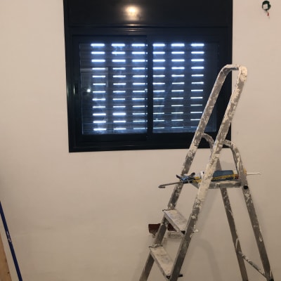 חלון אלומיניום עם תריסים סגורים וסולם צבוע