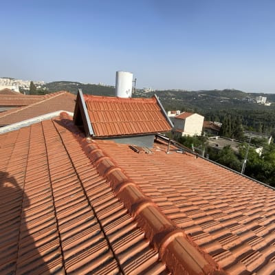 גג רעפים אדומים עם ארובה ומבנה קטן
