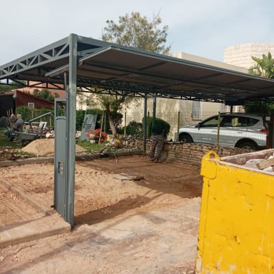 מבנה מתכת בבנייה עם מכולת פסולת צהובה