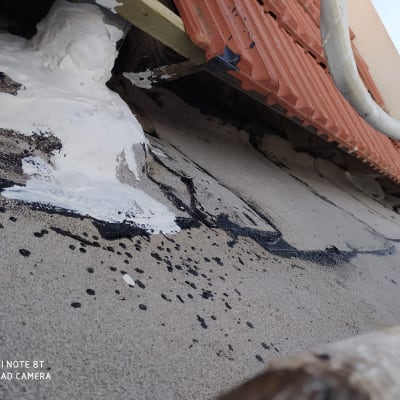 חומר איטום לבן ושחור על גג ליד רעפים