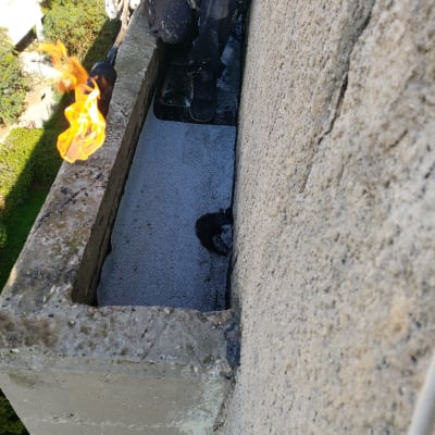 אדם משתמש במבער לאיטום גג בטון