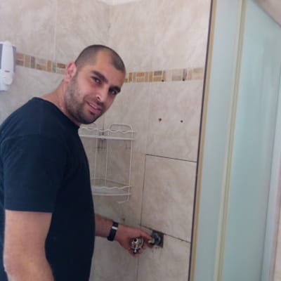 אדם מחזיק ברז בחדר אמבטיה