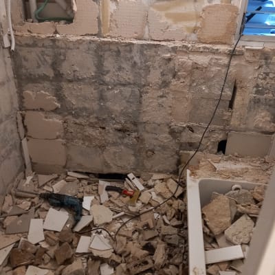 שיפוץ חדר עם קירות חשופים והריסות על הרצפה