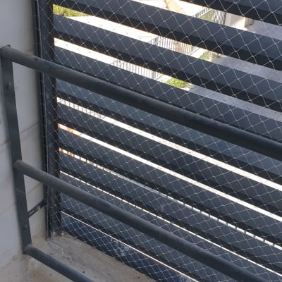 רשת מתכת מותקנת על מעקה למניעת כניסת יונים