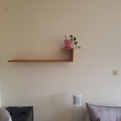 מדף עץ תלוי על קיר עם עציץ קטן