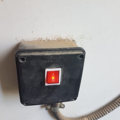 מתג חשמלי עם נורית חיווי אדומה על קיר