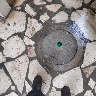 פתח ביוב עגול ברצפה עם רגלי אדם